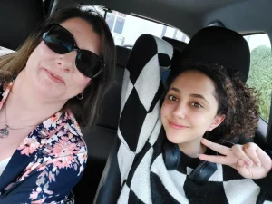 A picture of a student and their Educational Guardianship in the car. The student is happy.